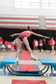 Young female gymnast performing jump on trampette