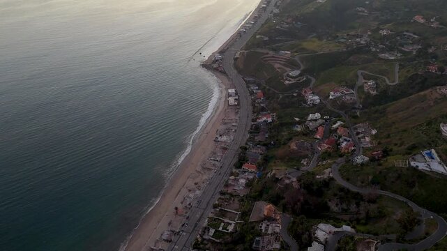 Aerial view of the Pacific ocean meeting the coast along California 1, the rugged terrain dotted with houses, Malibu, California, United States.