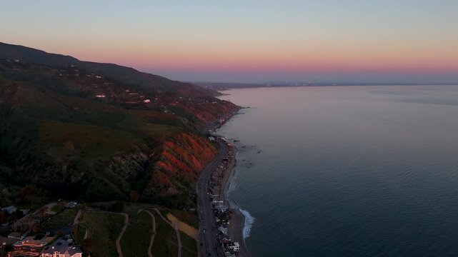 Aerial view of the Pacific Coast Highway winding along the rugged coastline against the backdrop of rolling hills, Malibu, California, United States.