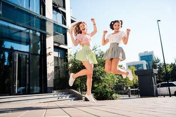 Playful young friends jump in the city sunshine as stylish travelers enjoy urban lifestyle and...