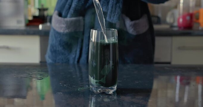 Pour a water into a glass with spirulina, audio included