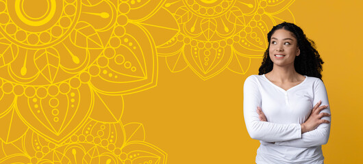 A woman stands with arms crossed, smiling at the camera. Behind her is a vibrant yellow background featuring intricate patterns. The scene captures a cheerful moment where she looks confident. © Prostock-studio