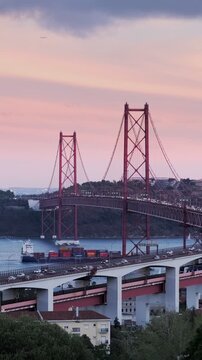 View of Lisbon view from Miradouro do Bairro do Alvito tourist viewpoint with Tagus river, traffic on 25th of April Bridge, and Christ the King statue at sunset. Lisbon, Portugal. Camera pan