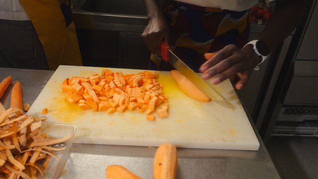 Professional chef preparing fresh cherry tomatoes for cooking traditional African dishes, making sweet potato broth and various ingredients on a stainless steel kitchen counter