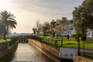 Fototapeta premium Ortszentrum von Ferragudo an der Algarve mit Palmen, Spielplatz und Brücke zwischen den traditionellen Häusern.