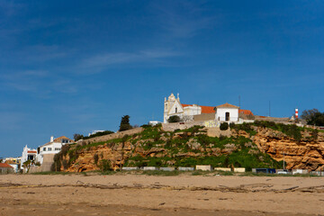 Obraz premium Blick auf die Kirche von Ferragudo mit Gartenanlage, erhöht auf einem Hügel über dem Strand an der Algarve