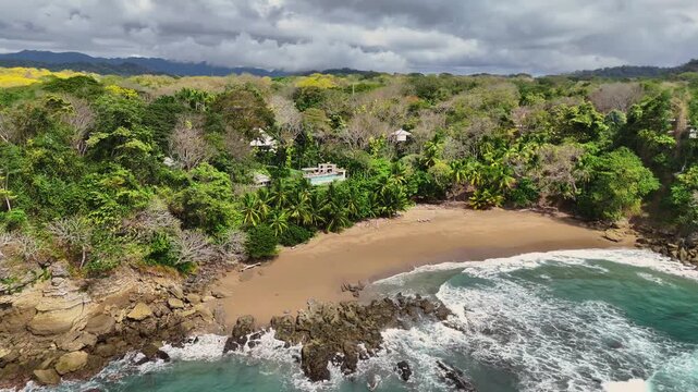 Aerial view of the lush forest meeting the sandy beach and turquoise waters, creating a vibrant contrast of colors and textures, Tambor, Puntarenas Province, Costa Rica.