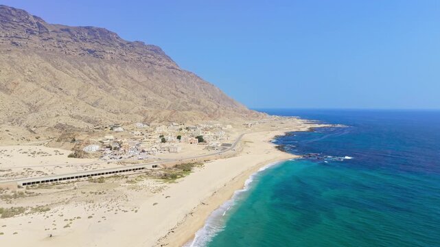 Aerial view of a coastal settlement and mountains bordering turquoise water along the Gulf of Aden in the Car Madow region of Somalia.