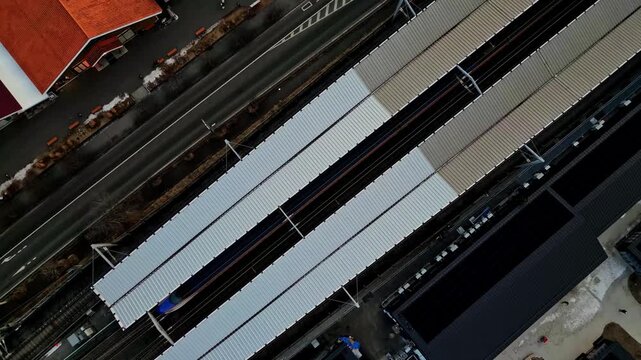 Aerial view of train station platforms with trains, buildings, and a road creating a geometric pattern of dark and light tones, Karuizawa, Nagano, Japan.