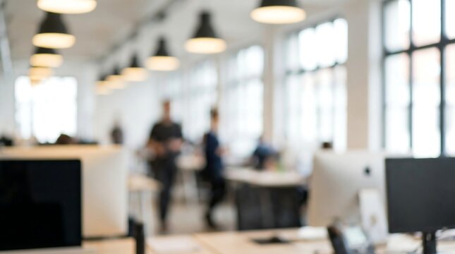 A blurred image of a bustling open-plan office shows modern desks, computers, and indistinct figures moving within the bright workspace.