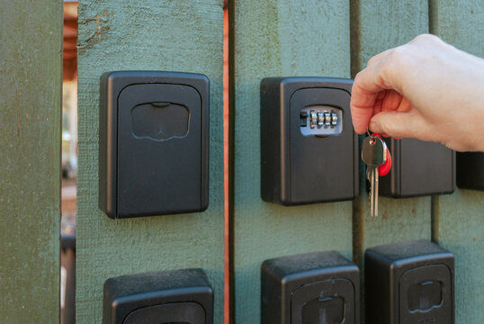 Hand opening key lock box on wooden fence