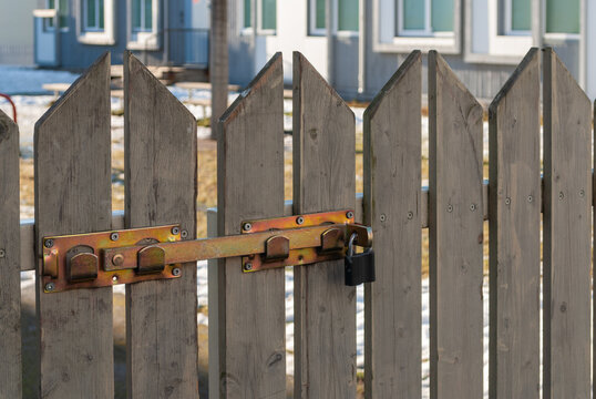 Wooden fence gate with metal latch and padlock