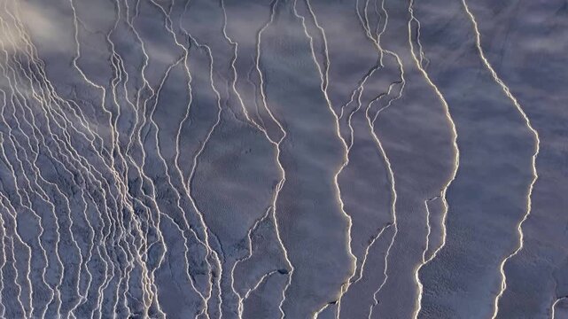 Aerial view of a contrasting landscape showing dark toned terrain etched with bright white lines creating texture, Grindavikurbaer, Iceland.
