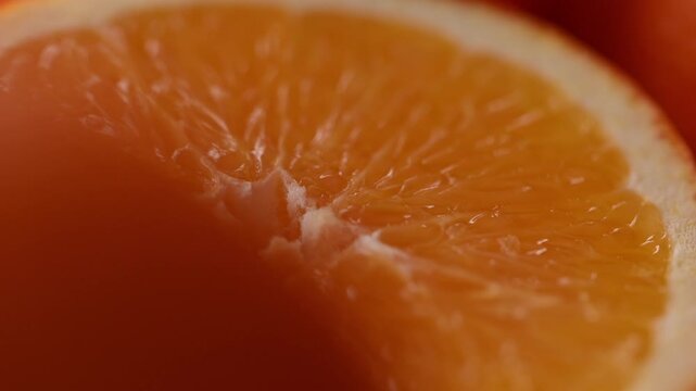Macro shot of fresh orange slice with juicy citrus pulp and natural fruit texture. Bright ripe ingredient with slow motion, healthy citrus concept for cooking, recipes, desserts and fresh food.