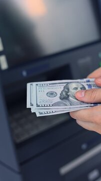 Close up view of woman hands counting American dollar banknotes (USD) in ATM. Concept of saving money for retirement, cash settlement, financial goals, success, literacy and income planning in USA.