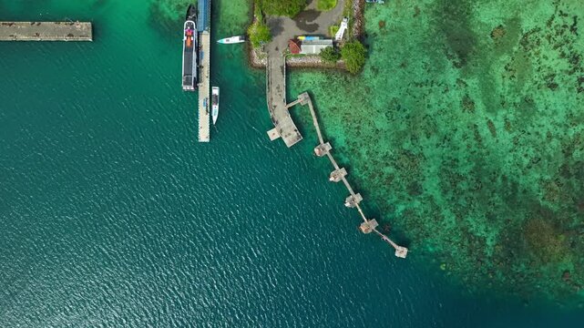 Aerial view of several boats docked at Karimunjawa ferry harbour, contrasting with the turquoise shallow waters and the deep blue sea, Karimunjawa, Central Java, Indonesia.