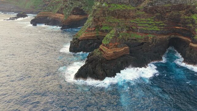 Aerial view of waves crashing against the rugged volcanic cliffs of Roque de El Cagado in Santa Ursula on the island of Tenerife, Spain