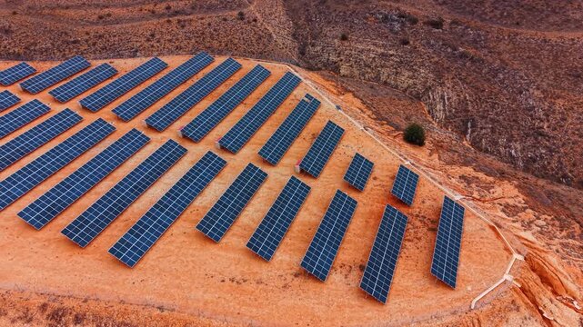 Circling around the rock with plain top covered with the rows of photovoltaic cells. Site for green energy production in the wilderness.