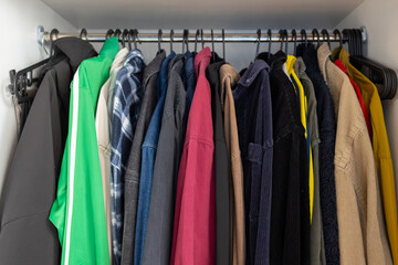 Fototapeta premium Organized wardrobe clothes hangers multicolor decluttering closet organization minimalism tidy neat arranged domestic lifestyle home storage