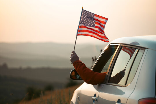 Man in the car holding a waving american USA flag.