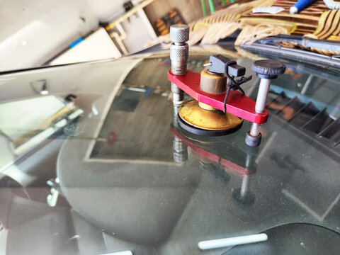 Car glass chip repair tool is placed on windshield to fix damage in local auto shop