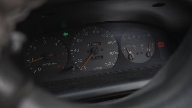 The dashboard of an old car, speedometer and tachometer, engine running, left turn signal on