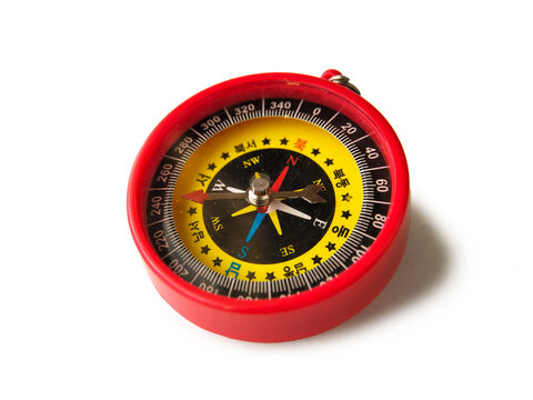 A red compass with a round casing rests on a white background. 