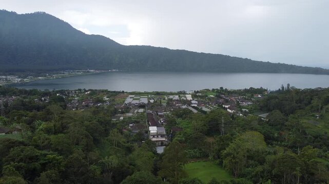 Aerial drone hovering and slowly moving right overlooking Lake Beratan near Bali Botanic Garden in Bedugul, Indonesia.