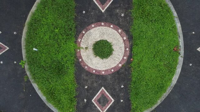 Cinematic aerial drone liftoff in top down view above garden square at Bali Botanic Garden in Bedugul, Indonesia.