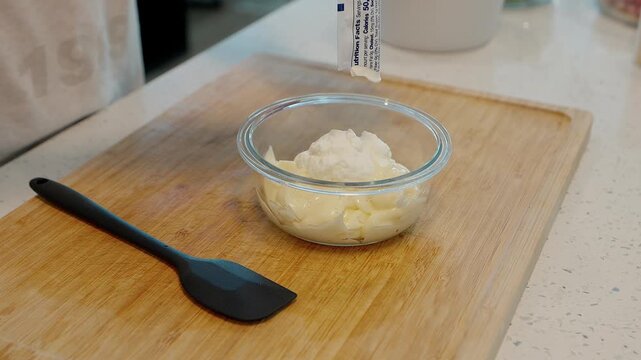 stockclose up of a hand squeezing greek yogurt into a bowl of creamy mayonnaise