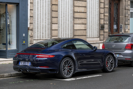 Nancy, France - February 28th 2026 : View on a blue Porsche 991 Carrera 4S parked on a street with a car in front and the facade of an old building in the background.