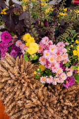 Colorful autumn flowers and golden wheat create a vibrant harvest display at a sunny market