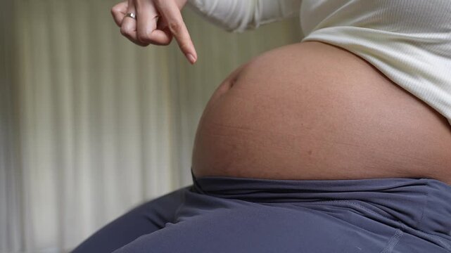 Pregnant woman gently touching and exploring her baby bump during pregnancy