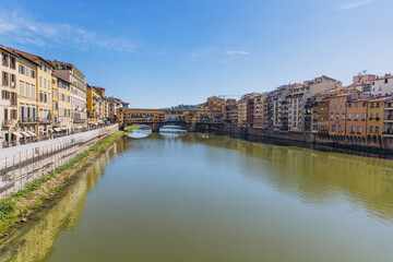 Obraz premium Ponte Vecchio bridge spanning Arno river in Florence, Italy, with historic buildings lining the banks