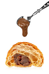 Spoon with creamy chocolate spread dripping above cut croissant with chocolate filling, flaky...