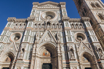 Fototapeta premium Florence Cathedral, Santa Maria del Fiore, showcasing its detailed colorful marble facade, round windows, and sculptural elements