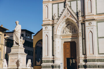 Dante Alighieri statue standing in Piazza di Santa Croce, Florence, Italy, with the Basilica di...