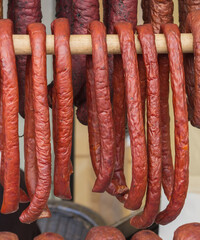 Domowe kiełbasy wiszące w wędzarni, tradycyjne wyroby mięsne podczas wędzenia, rzędy wędlin w zbliżeniu. © Henryk Guziak