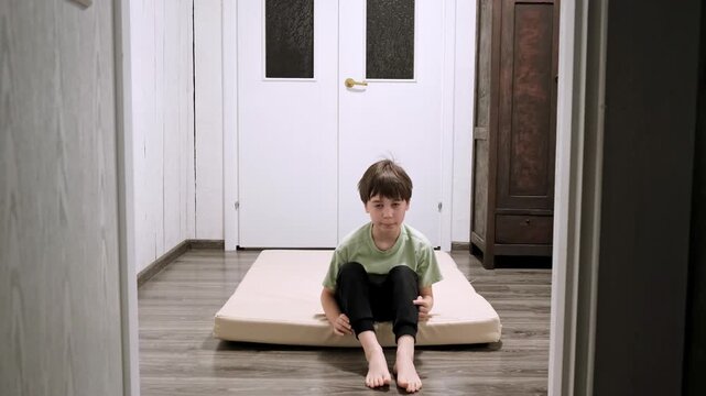 Caucasian boy doing somersaults back and forth on sports mat in home interior. Children workout. Happy child strengthening the muscles. Strong body. Kid does sports exercise. High quality 4k footage.