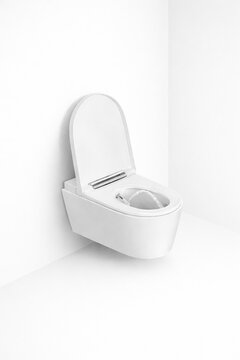 White toilet bidet on a white wall in the bathroom.