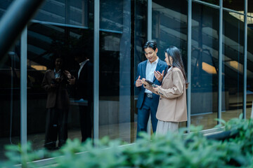 Business colleagues businessman and woman sitting and discussing,planning work using tablet outside...