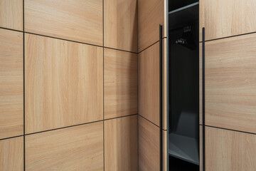 Minimalist wooden cabinet with natural oak panels and black vertical handles contemporary interior furniture detail