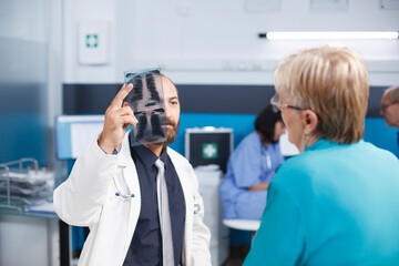 Obraz premium Mature patient consults specialist for back pain recovery. Physiotherapist provides medical support and suggests exercises. Treatment in hospital consulting room with digital X-ray.