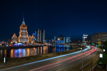 Obraz premium Night view of high-rise stalinist building and Moscow river with Moscow City buildings in the background in Moscow, Russia.