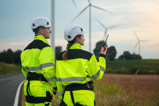 Wind energy workers monitoring turbines rural landscape photo evening light side view renewable energy concept