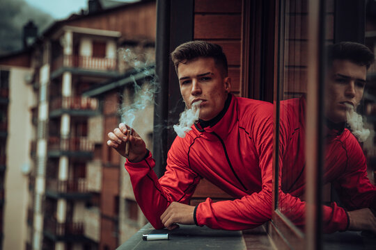 Young men smoking while looking out of window