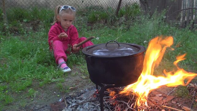 Child Waiting Food Cooking in a Pot for Eating, Rustic Kid in Yard, Countryside Children