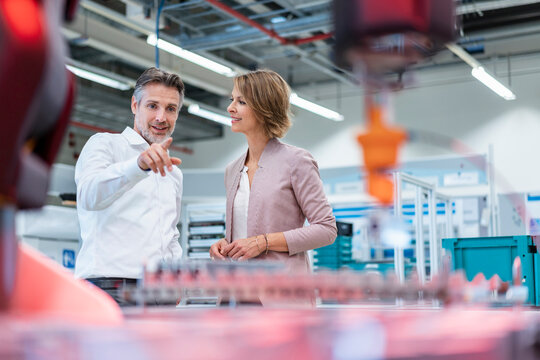 Businessman and businesswoman talking in a modern factory hall