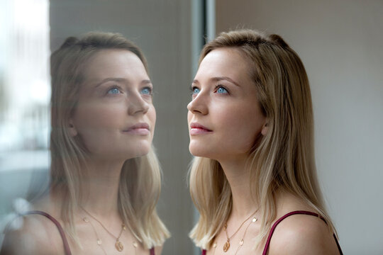Portrait of blond young woman and her reflection on windowpane