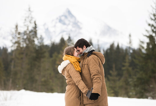 Happy young couple standing head to head in winter landscape